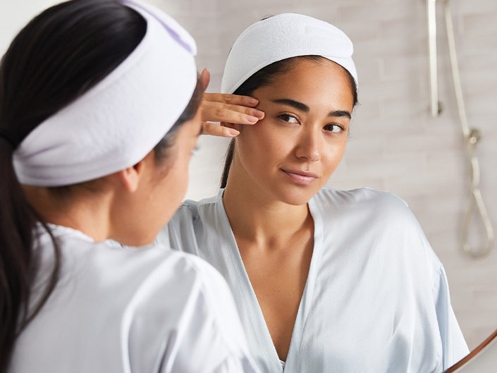 person touching eye area looking in a mirror