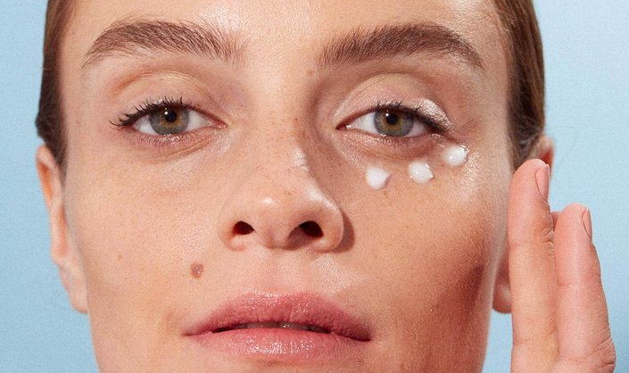 person applying eye cream under eye